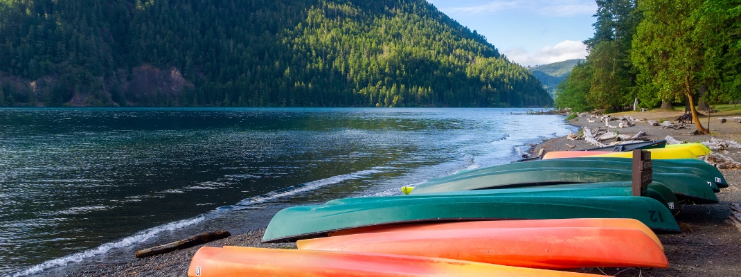 Row of colorful kayaks lying on the shore of Lake Crescent