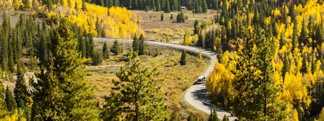 A rural mountain road with a winding "S" curve. Autumn landscape in Colorado. 